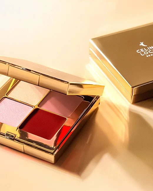 Paleta de sombras com quatro cores, com embalagem dourada, aberta sobre uma superfície clara, ao lado de uma caixa dourada fechada.