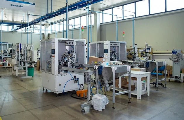 Fábrica com máquinas de impressão e produção automatizada.