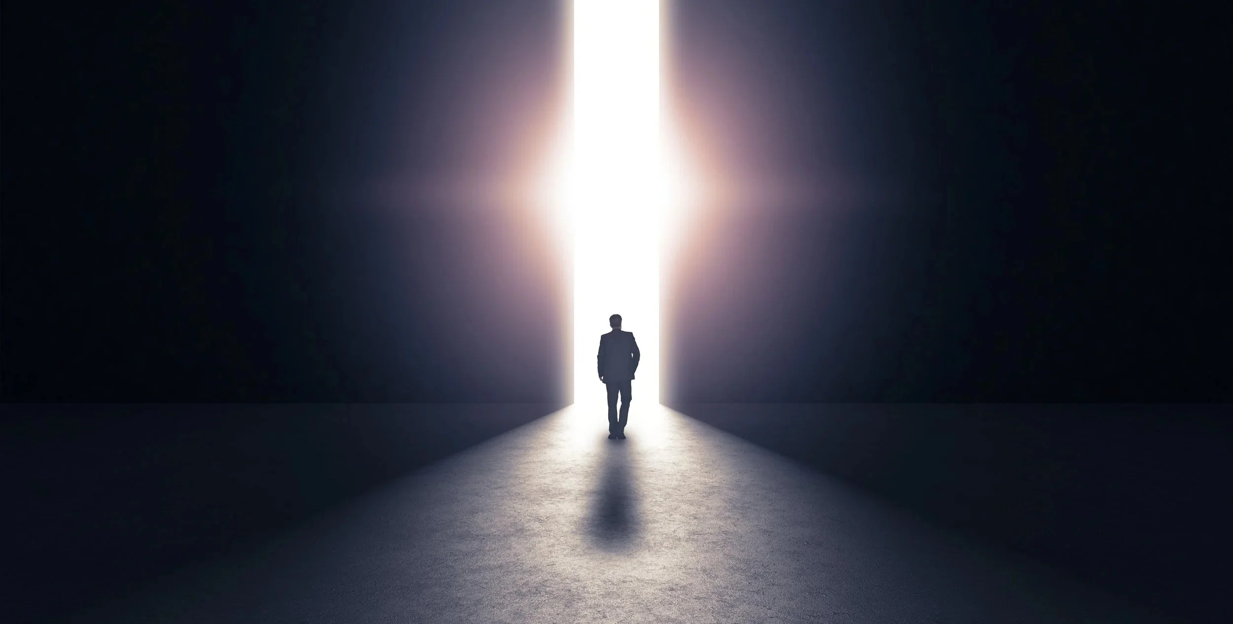 Individual walking to the light coming from within a dark room