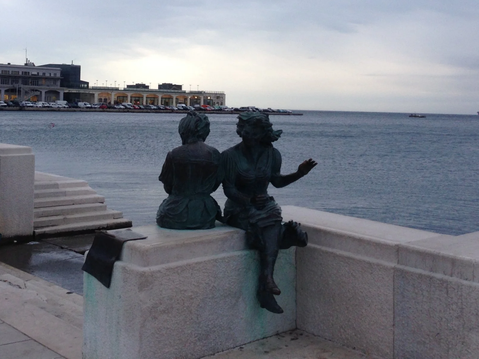 A couple sits at the edge of the ocean