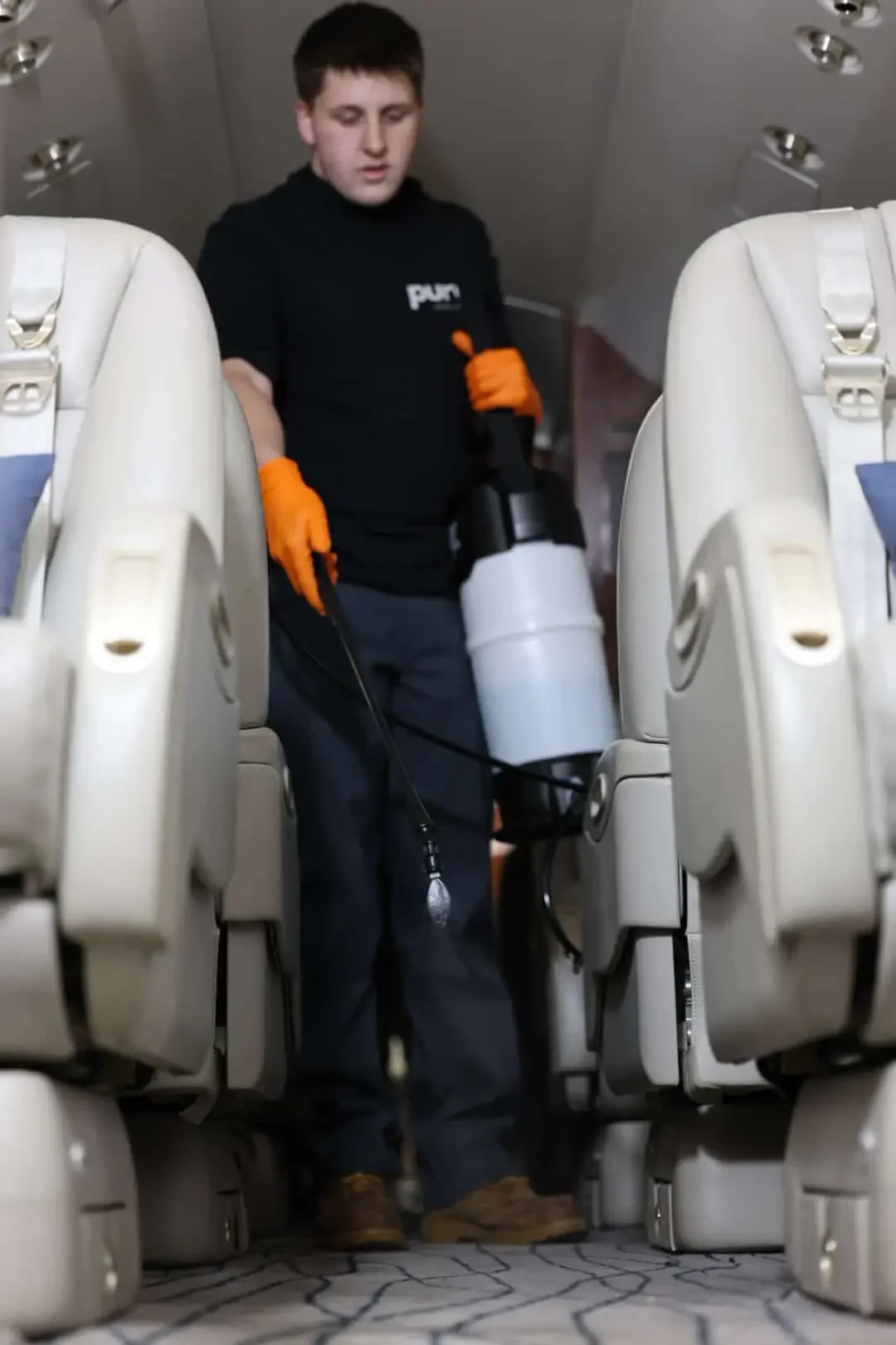 Pure Aircraft Disinsection technician applying WHO-approved permethrin 2% residual treatment to aircraft carpet