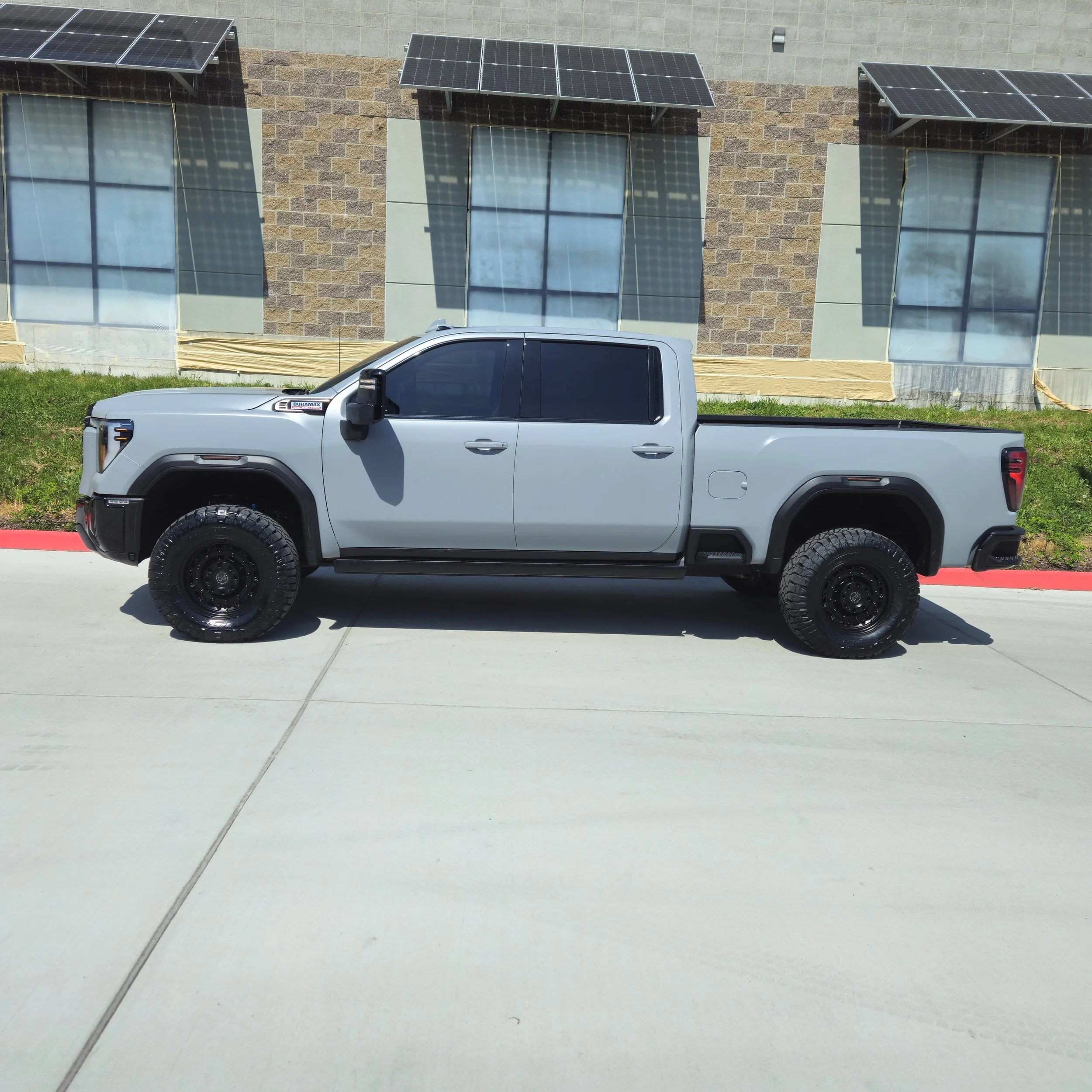 A white pickup truck parked in front of a building with solar panels on the roof and cables on the ground.