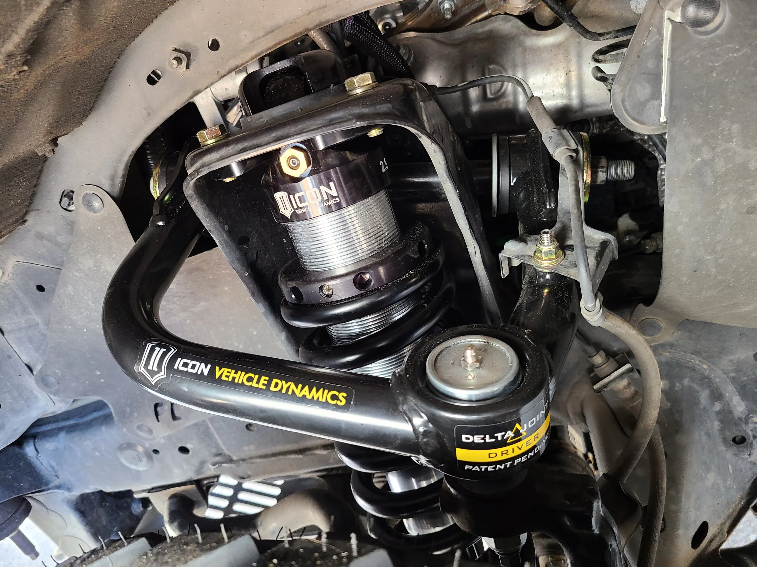 Close-up of off-road vehicle suspension system with a black coilover shock absorber marked 'Delta'.