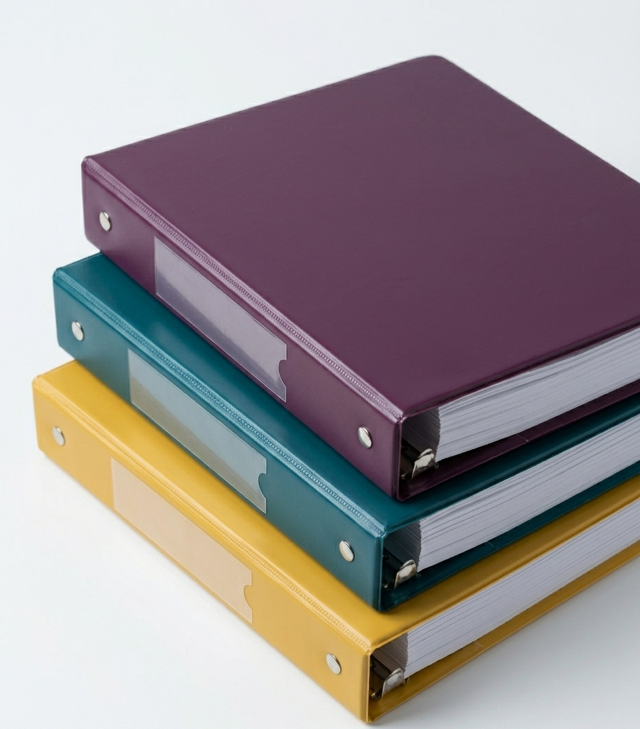Tres archivadores de colores morado, azul y amarillo apilados en orden creciente.