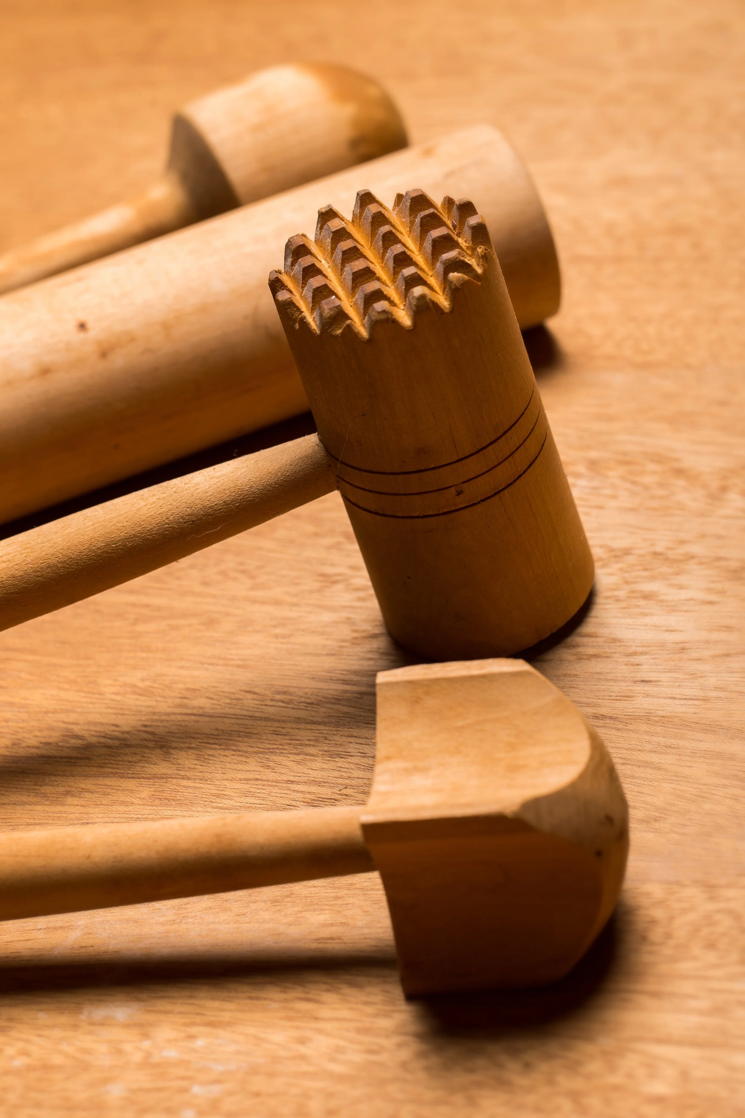 Une image montrant différents outils en bois avec des dents usées ou endommagées, sur une surface en bois.