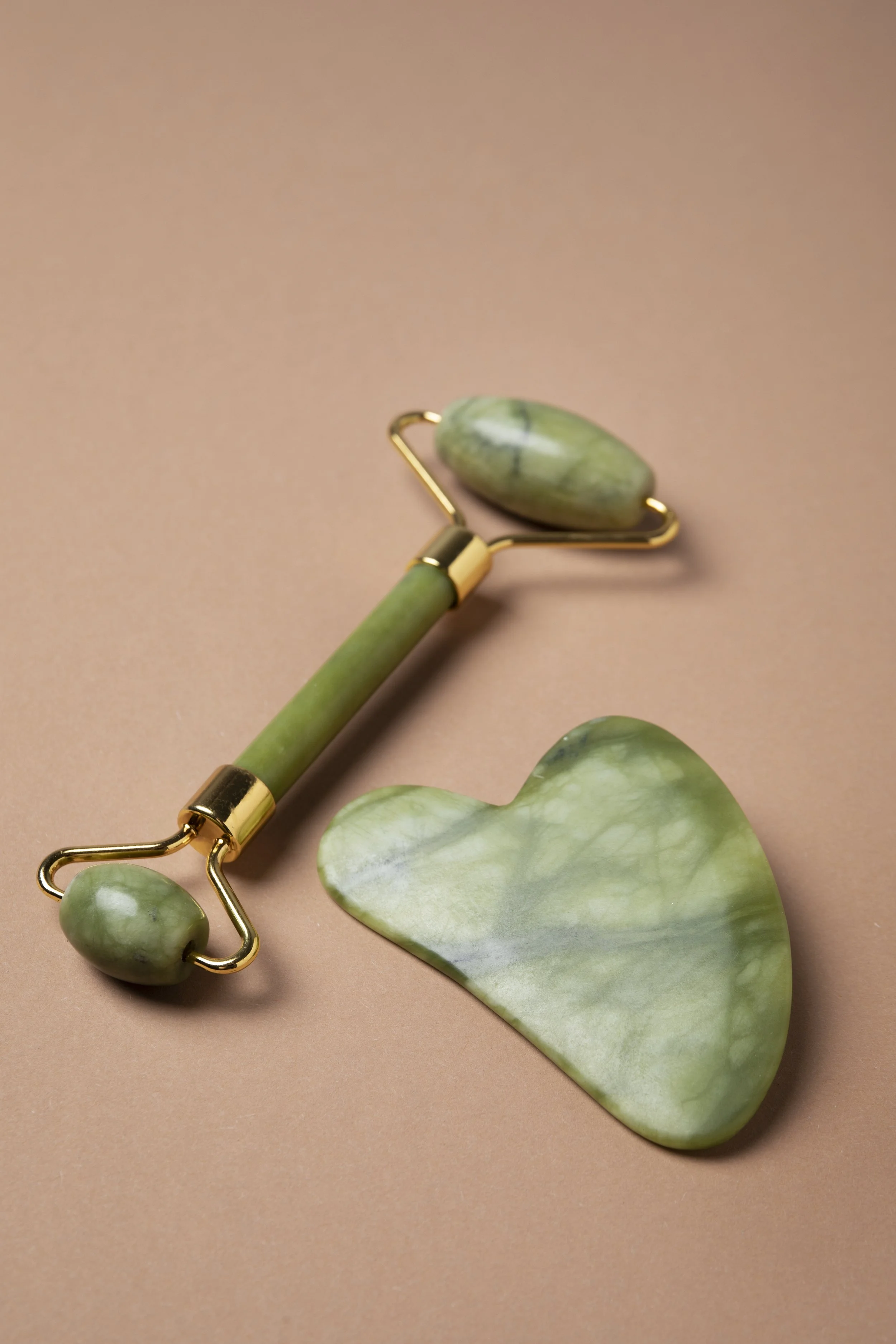 Rouleau de jade en forme de cœur et rouleau facial en jade sur fond rose