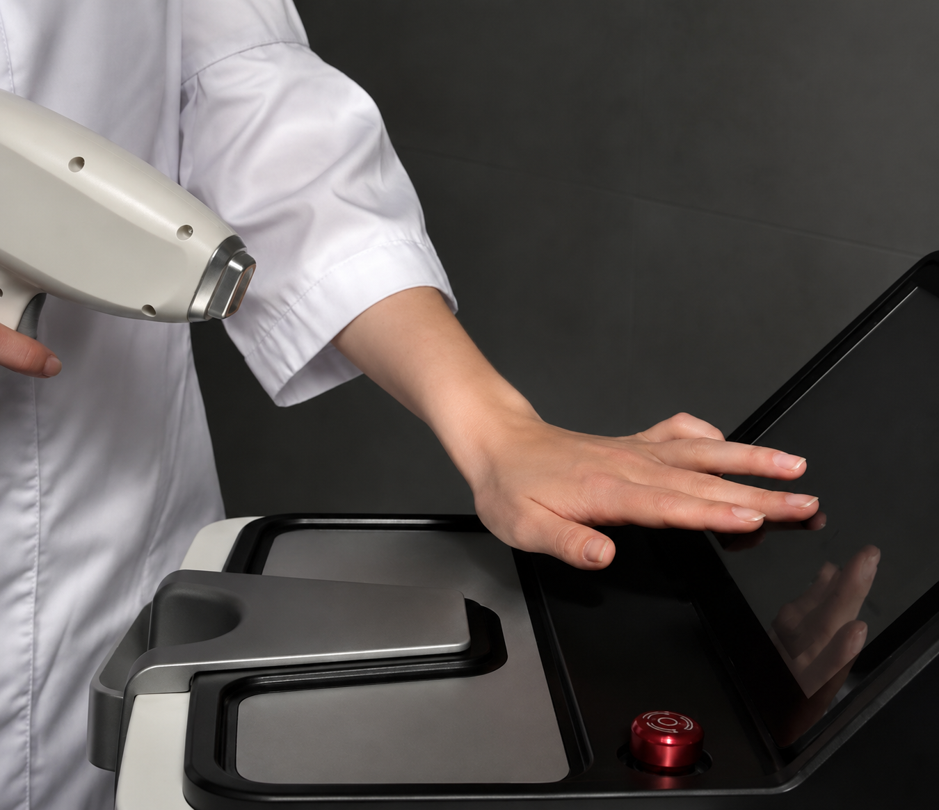 A person in a white lab coat operating a touchscreen device with a laser scanner nearby.