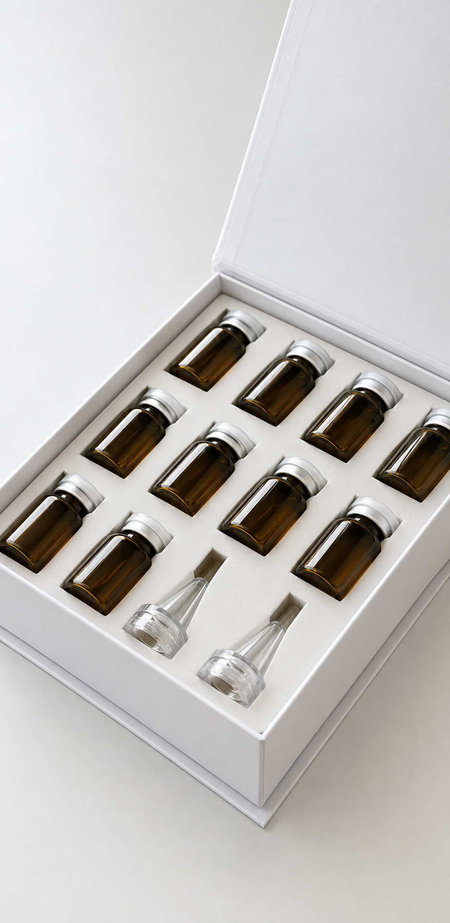 A white box containing twelve amber glass bottles with white caps and two glass droppers, arranged in rows, likely containing essential oils or tinctures.
