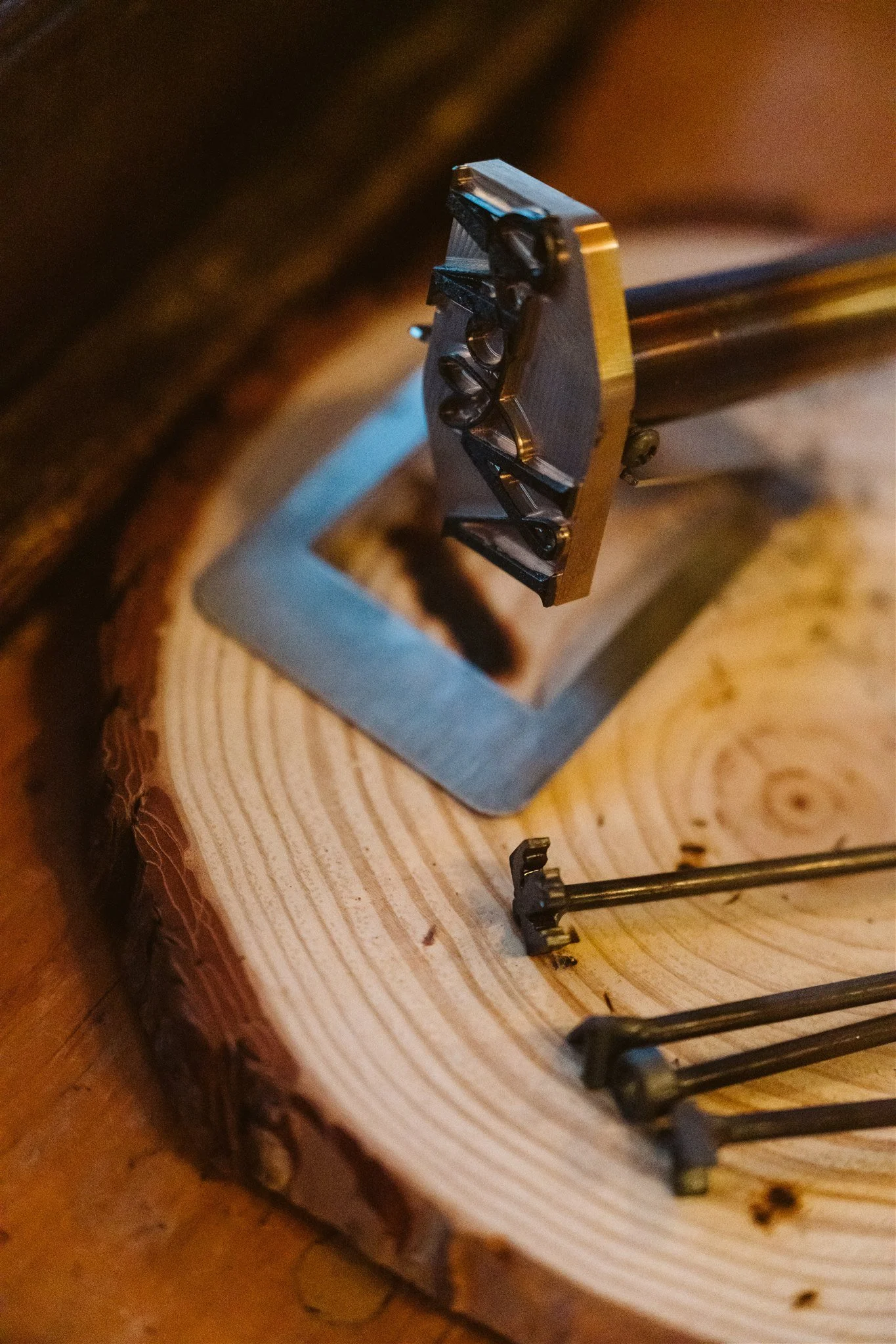 Close-up of a person's hand using a small clamp to hold a metal piece with screws onto a wooden surface for woodworking.