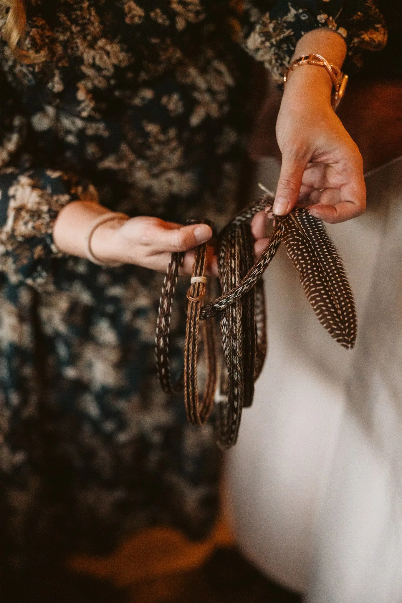 Person holding and examining a brown and black spotted feather.