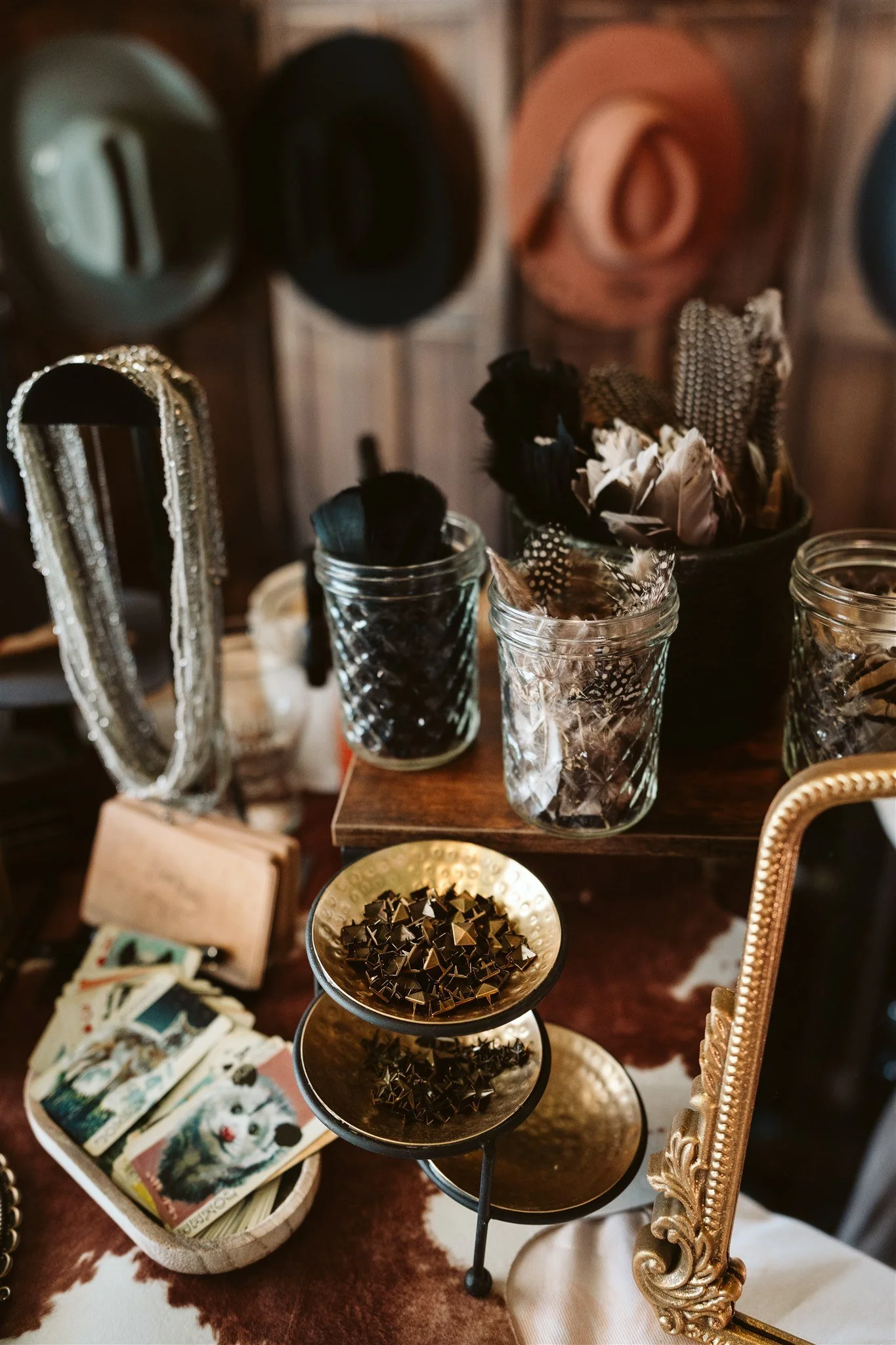 A display of various jewelry and decorative items including a picture frame with rhinestones, a set of three glass containers with feathers and jewelry, a bowl of star-shaped metallic objects, a basket of lotto or playing cards, and a large ornate go