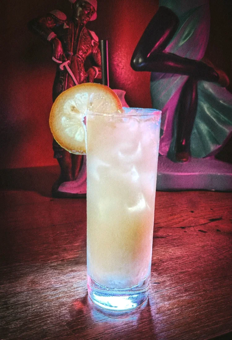 Tall absinthe cocktail with lemon wedge.