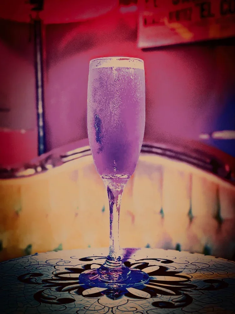 cocktail in a flute made with raspberries.