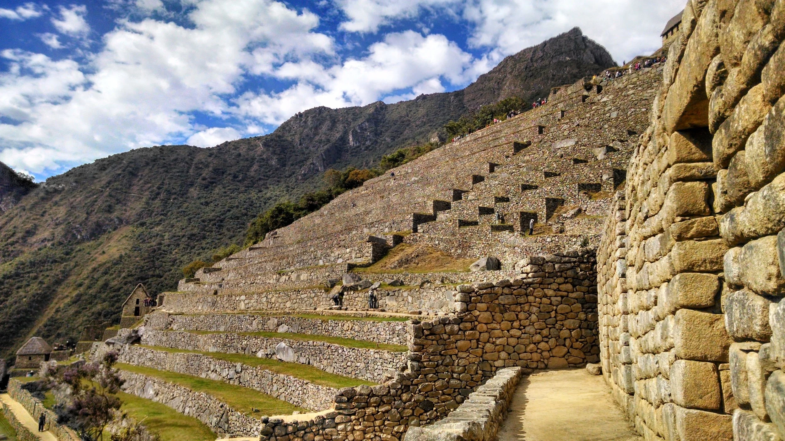 Ancient Incan terraced ruins on a mountain in Machu Picchu with a cloudy sky.