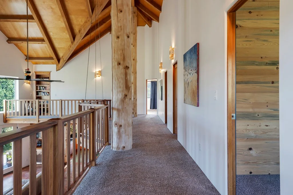 A hallway inside a house with wooden accents and art on the wall.