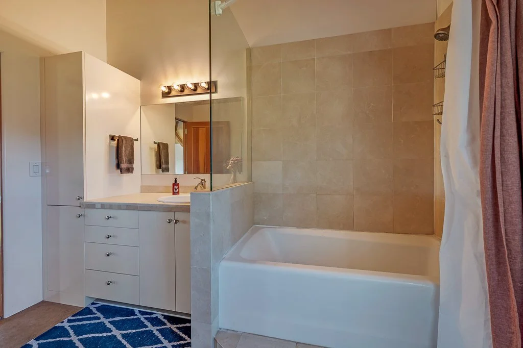 Bathroom with vanity, mirror, towels, bathtub, and shower curtain.