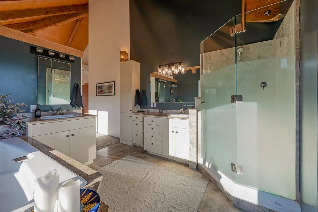 Bathroom with dual sinks, a glass-enclosed shower, a bathtub, and wooden ceiling beams.