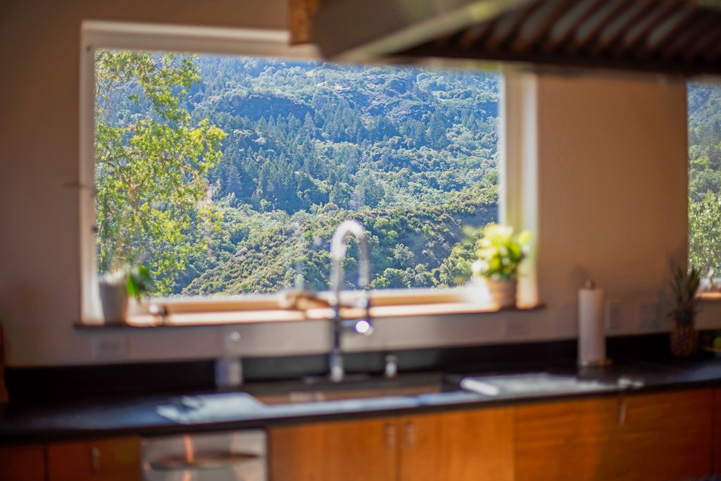 View of a lush green mountain landscape through a kitchen window.