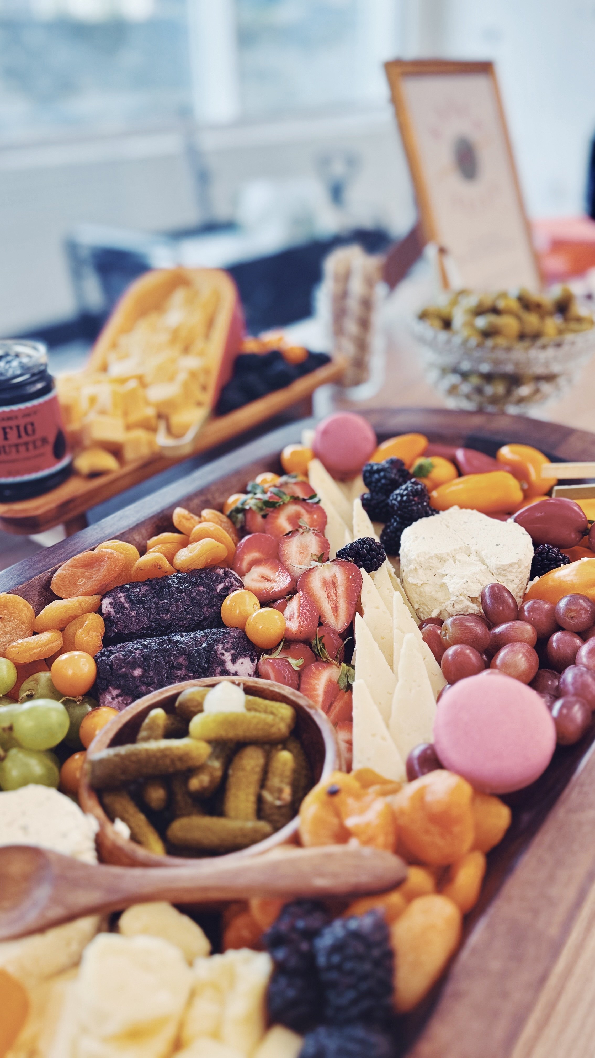 A wooden board with a cheese, berries, grapes, and Cookies and cream.