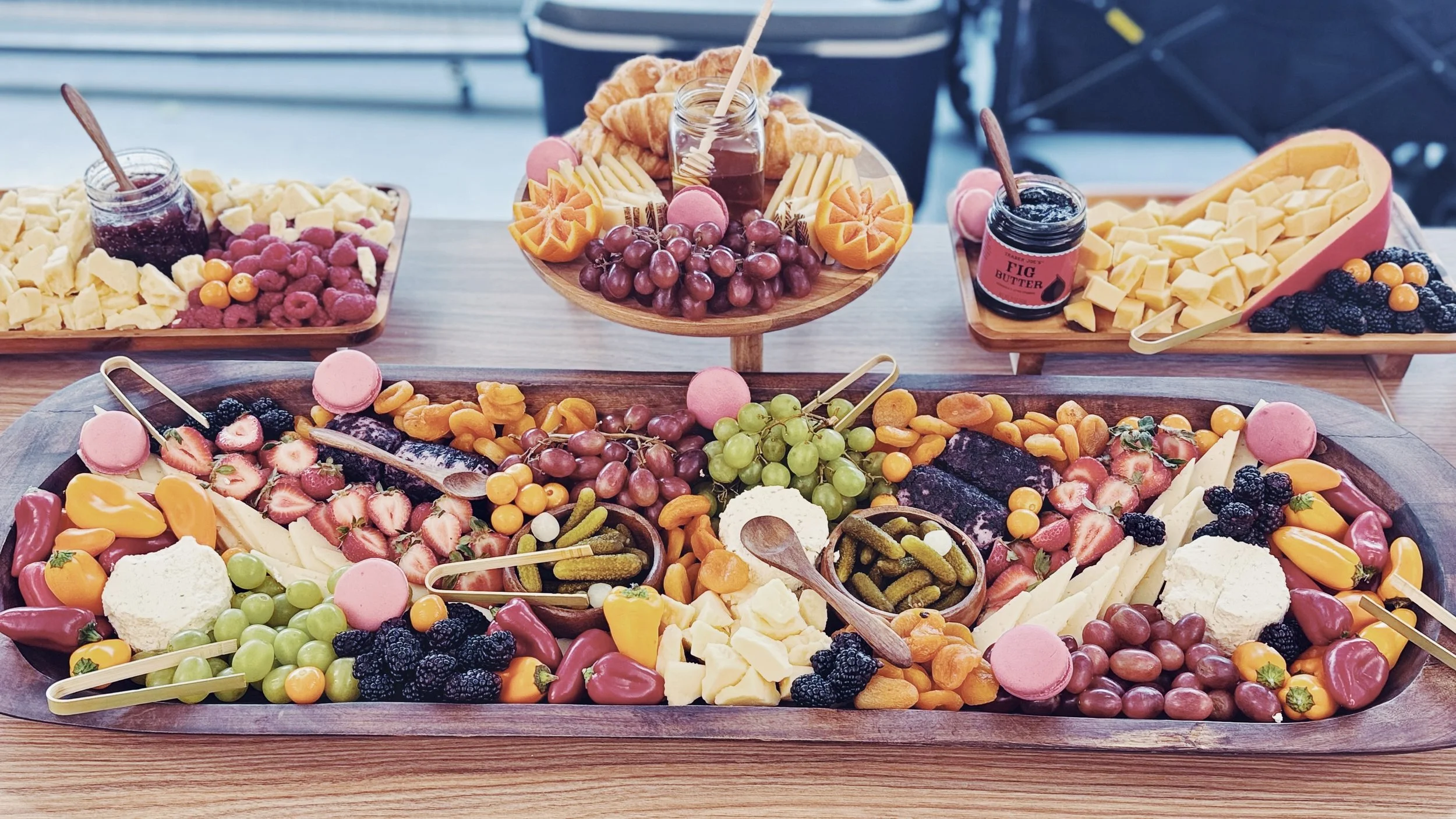 Assorted colorful fruit and dessert platter with cheese, grapes, berries, macarons, and chocolate