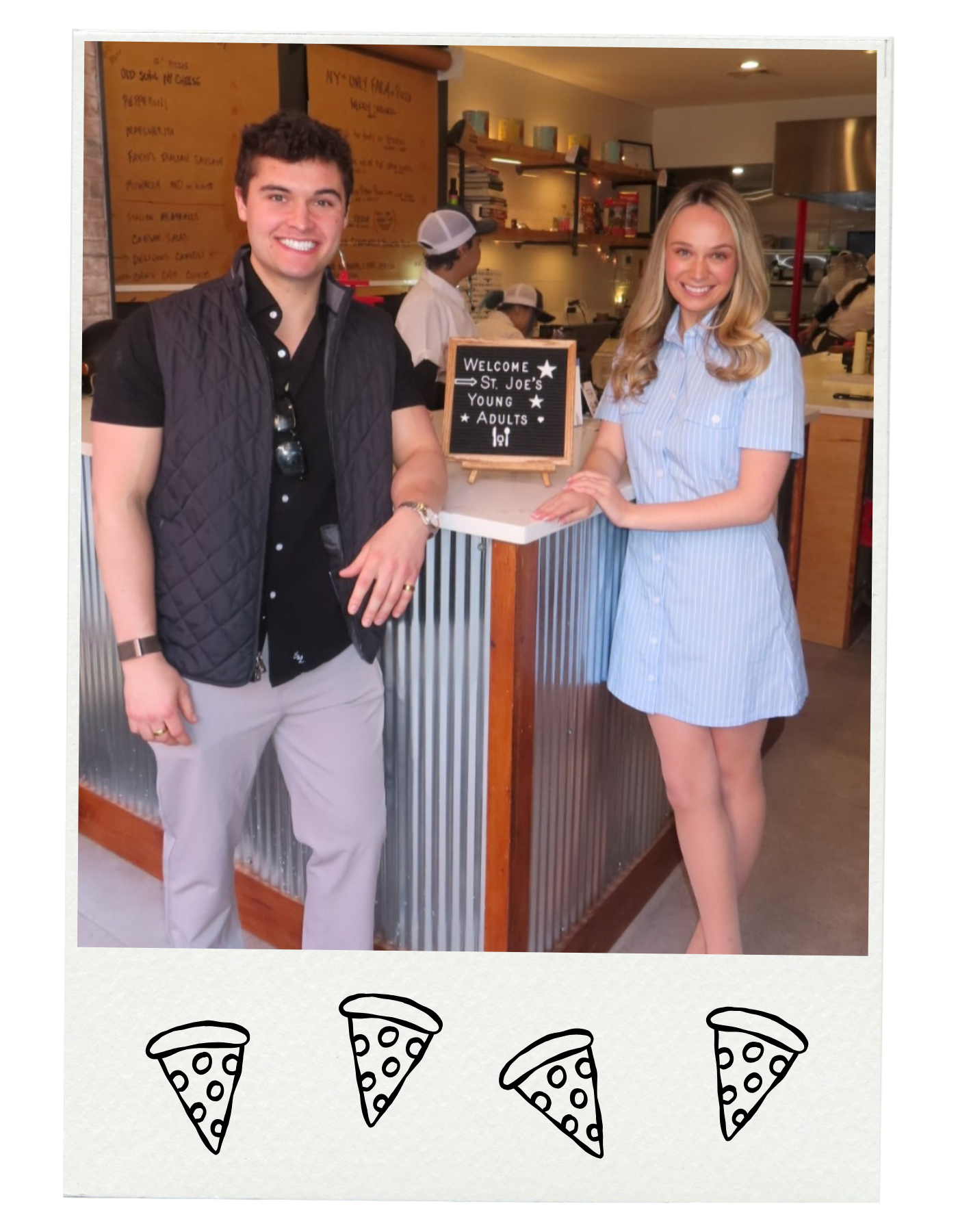 A man and woman smiling at a restaurant counter with a sign that reads "Welcome St. Joe's Young Adults." The man is wearing a black vest over a black shirt and light gray pants, and the woman is wearing a blue and white striped dress. In the background, there are kitchen staff and a menu board.