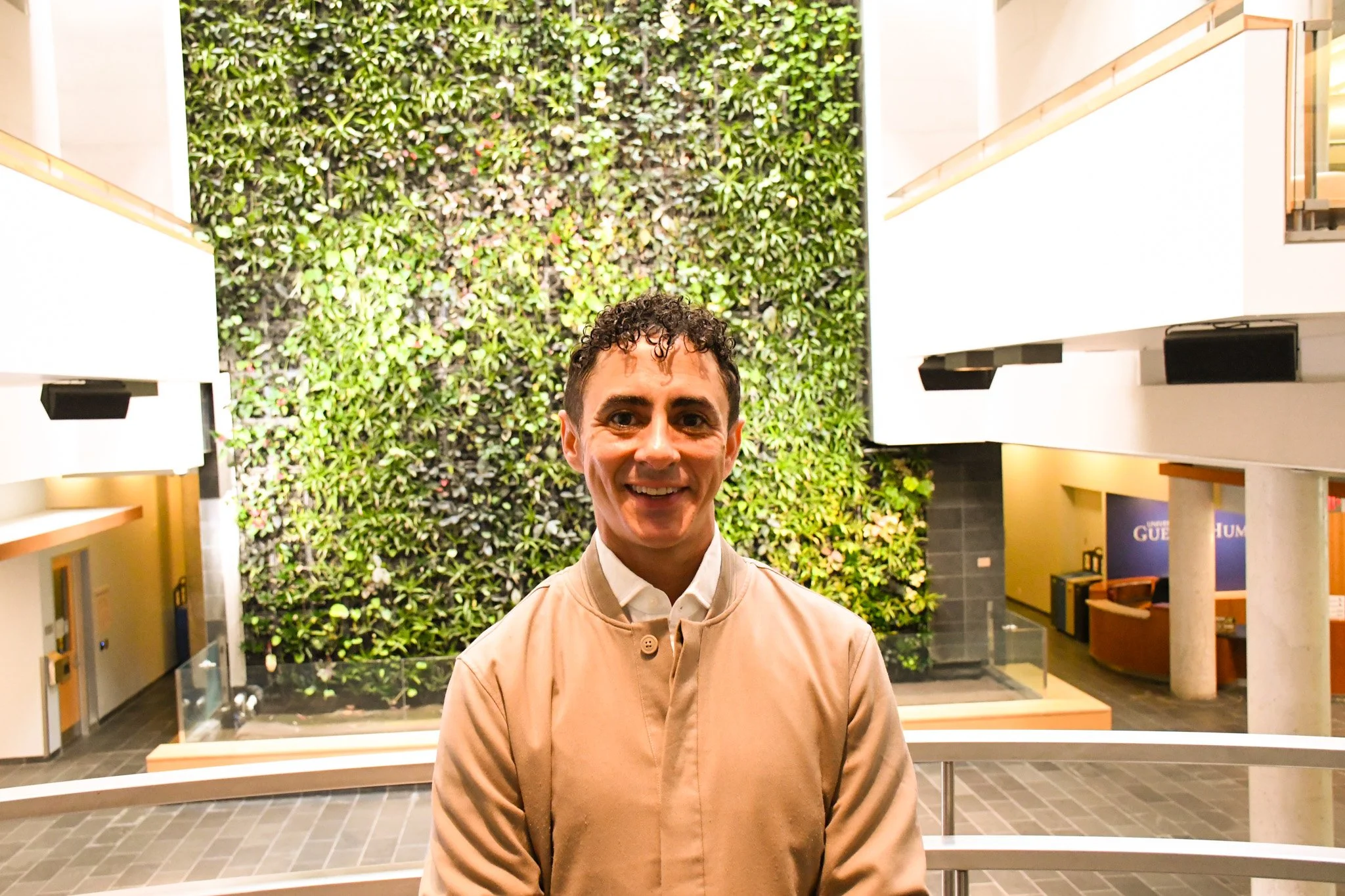 John Little standing in front of greenery wall at Clarity Family Coaching