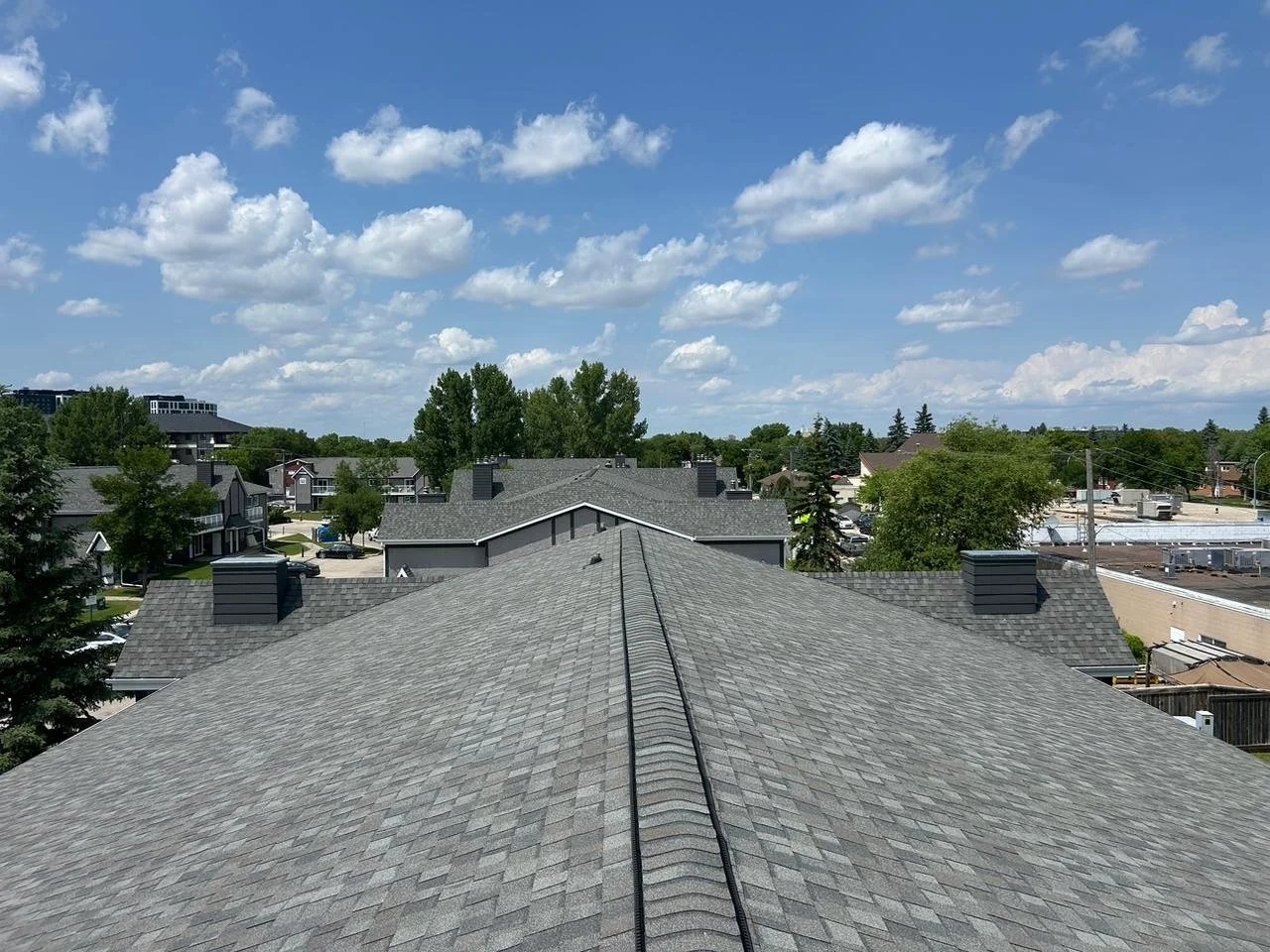 View of rooftops on a suburban neighborhood with blue sky and scattered clouds.