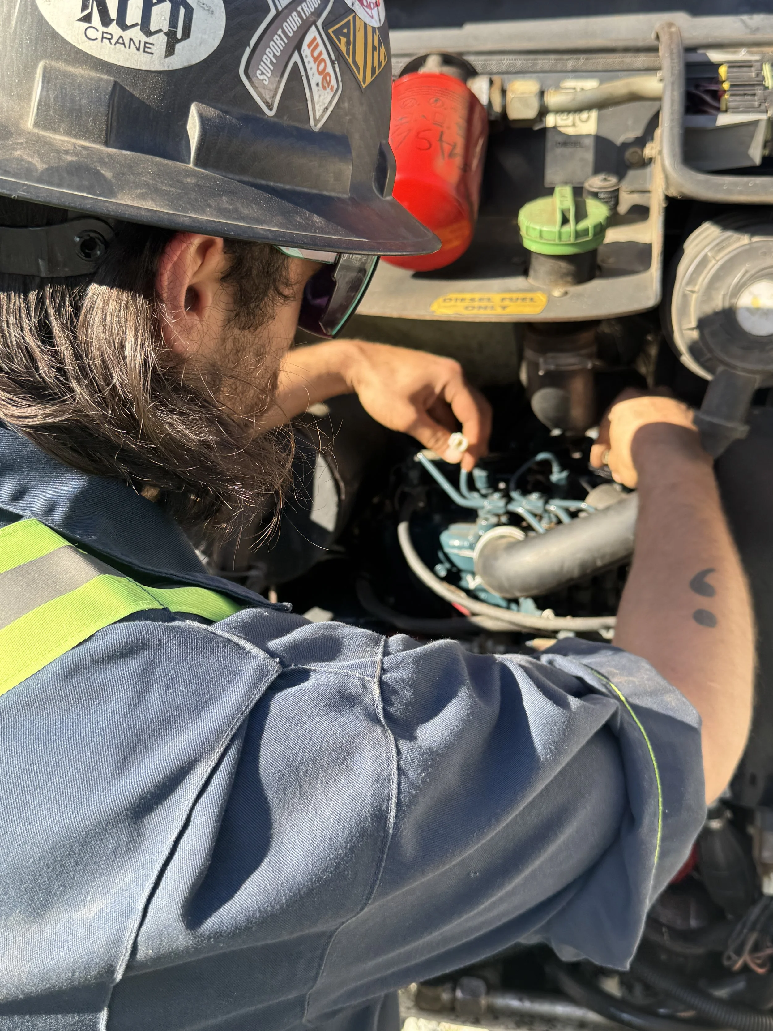 a mechanic wearing heatwaves working in the engine bay of an excavator