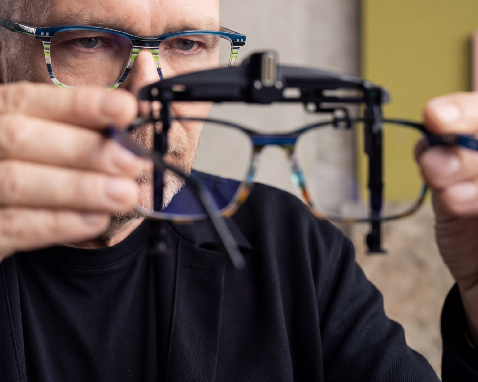 Optiker Ralf Überschär setzt eine Brille mit OptikamPad Zentriertestem Prisma Aufsatz einem Kunden auf