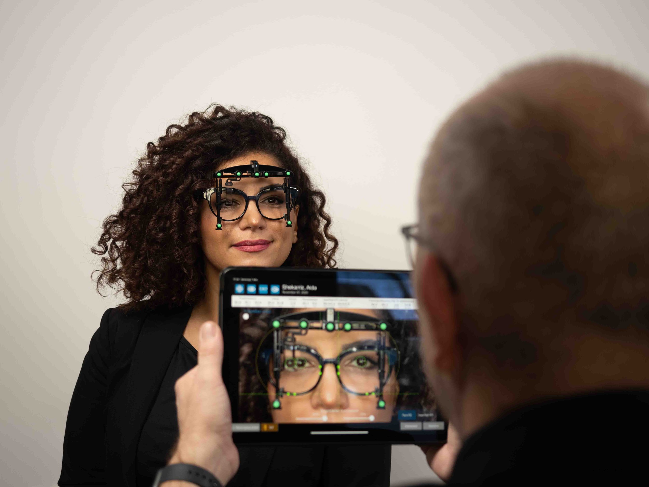 Kundin mit Brille und Prisma Aufsatz. Optiker mit iPad mit OptikamPad Zentriertestem
