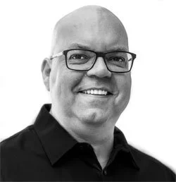 Porträt eines lächelnden Mannes, Optiker von Beruf, mit Brille, schwarz-weiß. 