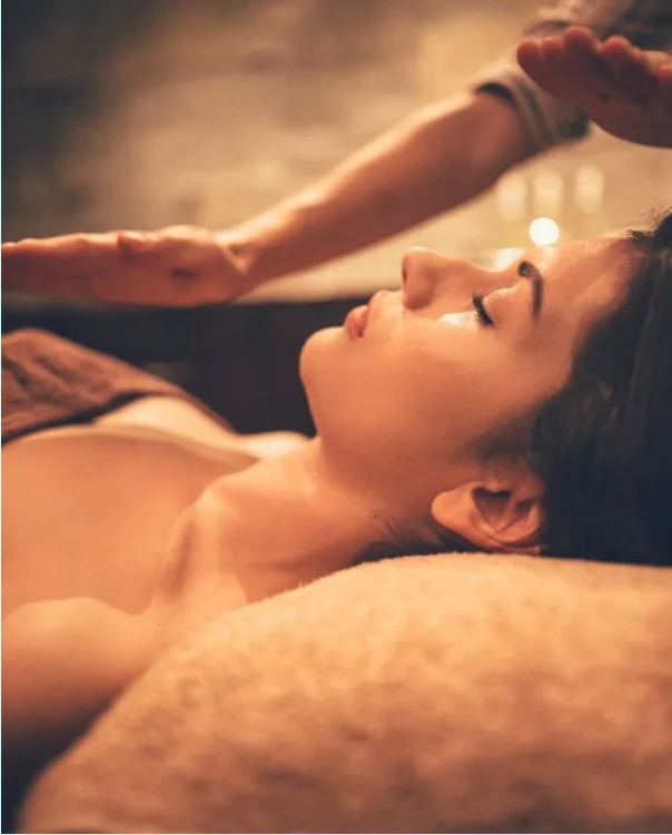 A woman lying down having reiki in a warm, relaxing setting.