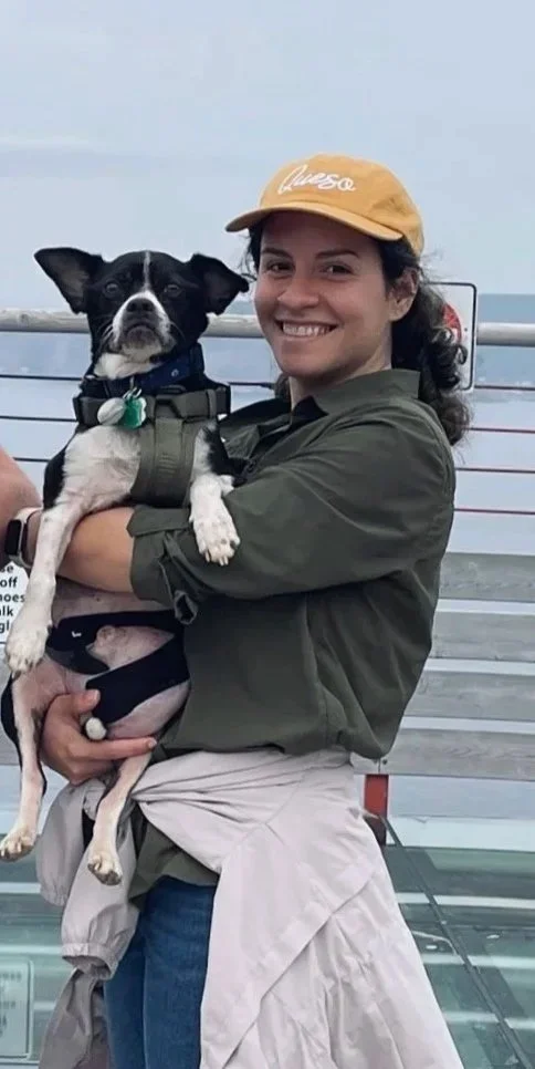 A woman pet sitter smiling and holding a black and white dog.