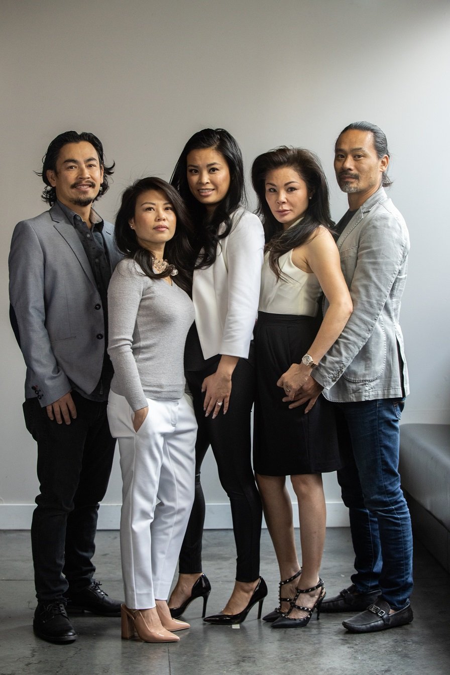 Group of five diverse professionals in business attire posing together indoors