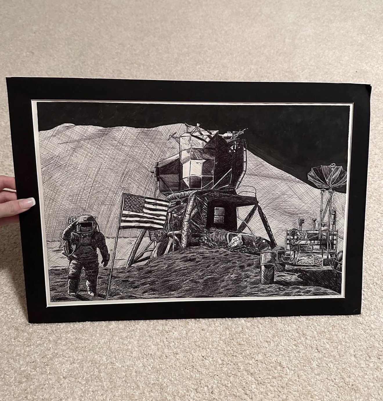 Black and white drawing of the lunar module on the moon's surface with an astronaut and American flag, and lunar rover in the background.