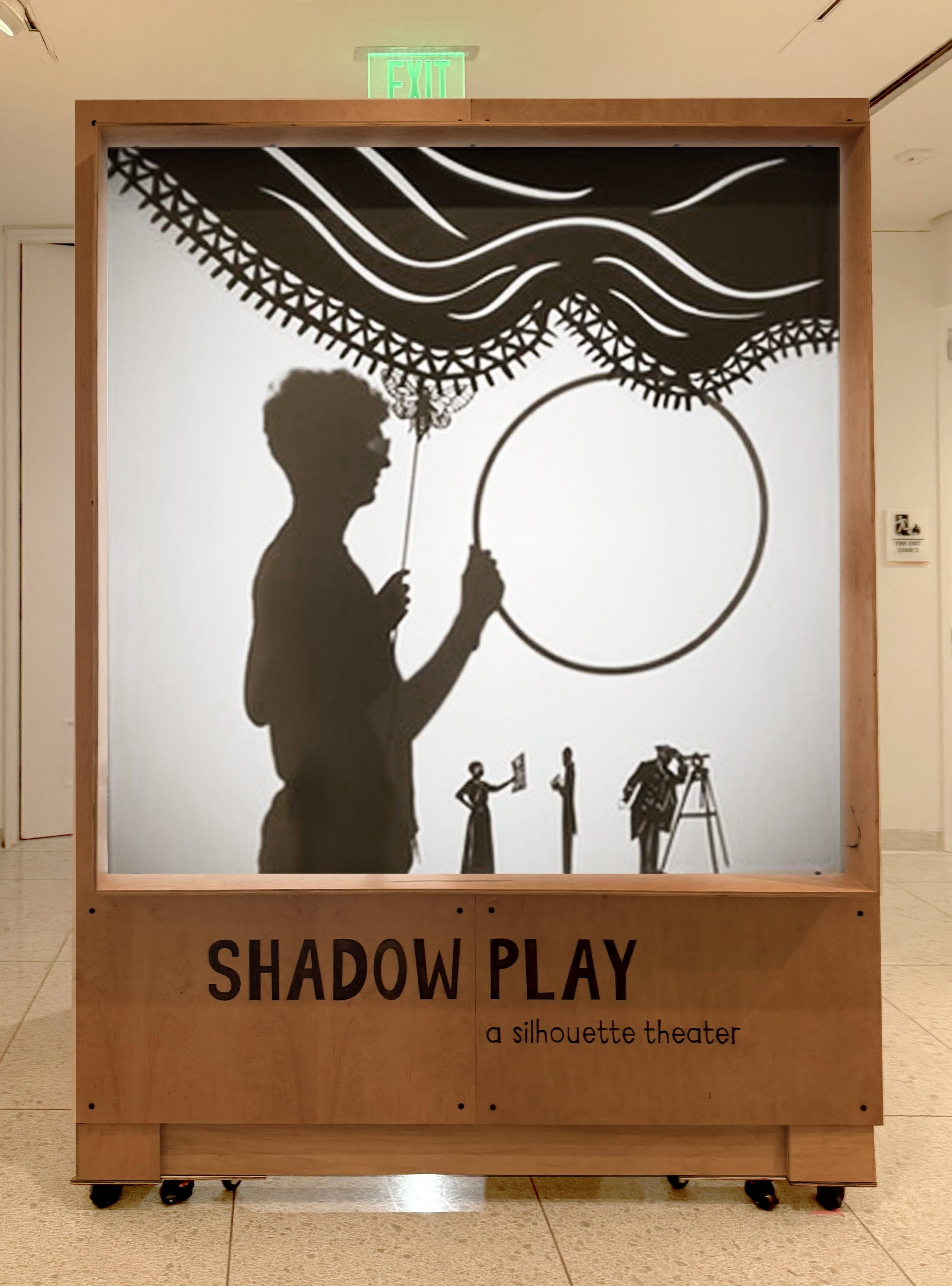 Museum display with black shadow silhouette artwork that depicts a person enjoying a custom-made museum display for Maryland Center for History and Culture, 'Shadow Play' and 'a silhouette theater' at the bottom.