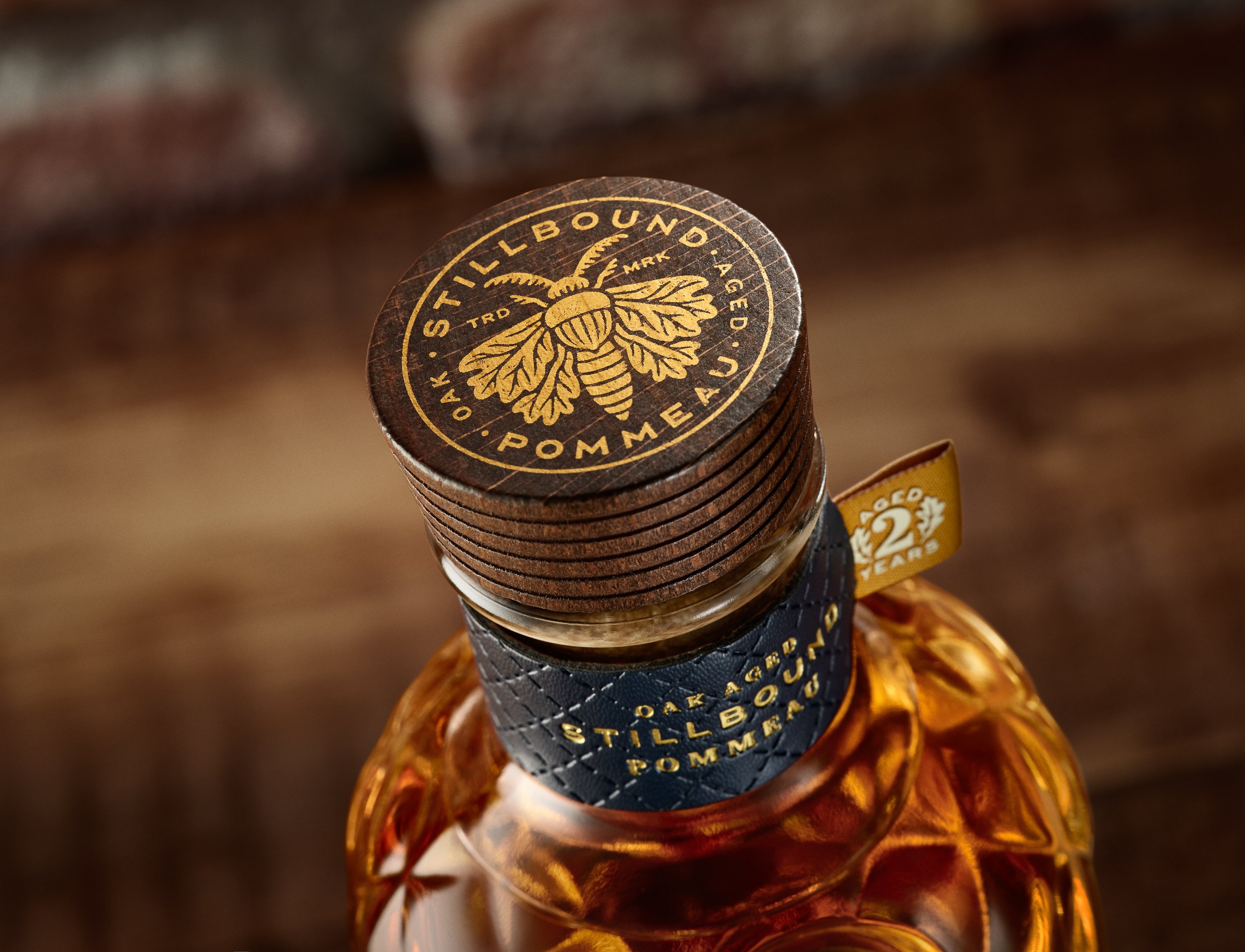 Close-up of a bottle featuring a black wax seal with a gold bee and the text 'Stillhouse' and 'Pomegranate' around it.