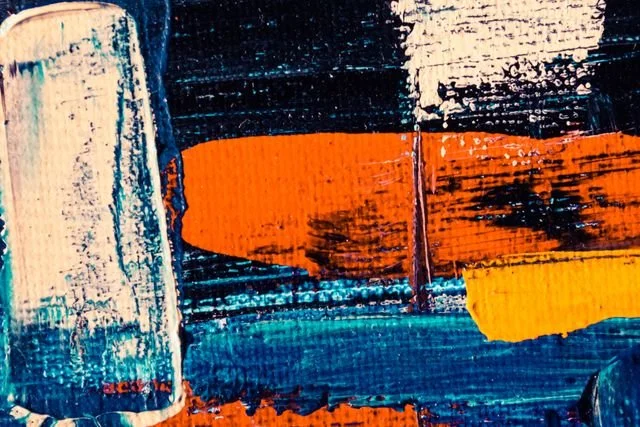 Close-up of a textured abstract painting with blue, orange, yellow, and black brushstrokes.