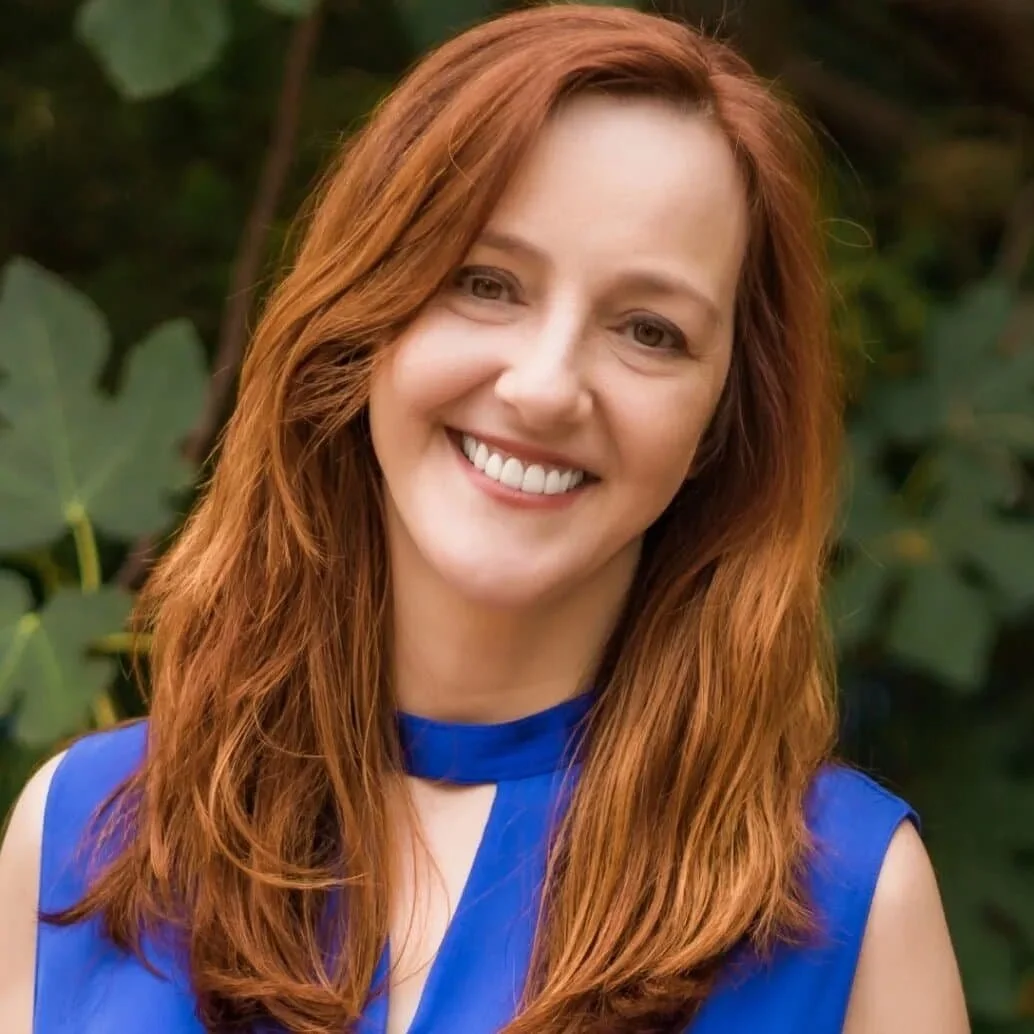 woman with red hair and a blue top smiling