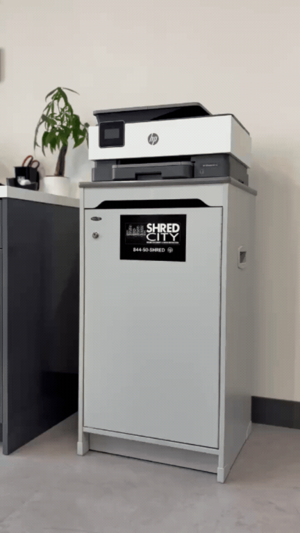 Office printer on top of a shredding machine in an office setting.