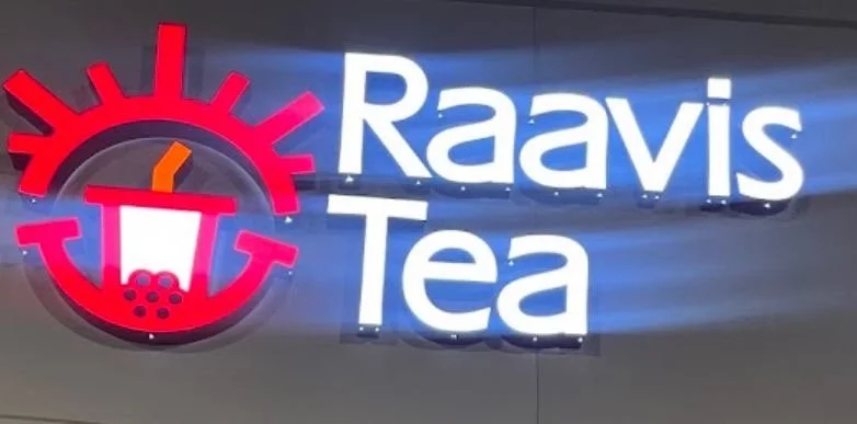 Sign for Raavis Tea with a stylized clock and a bubble tea drink illustration.
