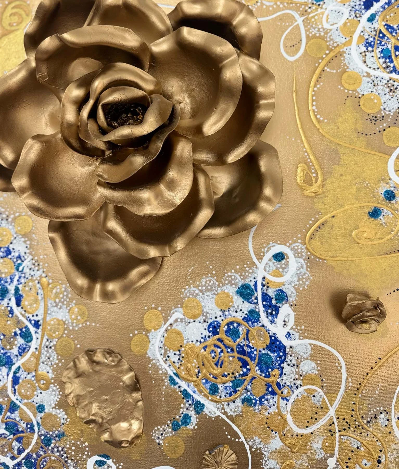 Patricia Edelman's "Golden Bloom" from her "Muse's Garden" series  features a large gold sculptural metallic flower and matching smaller flowers on a gold and blue patterned background.