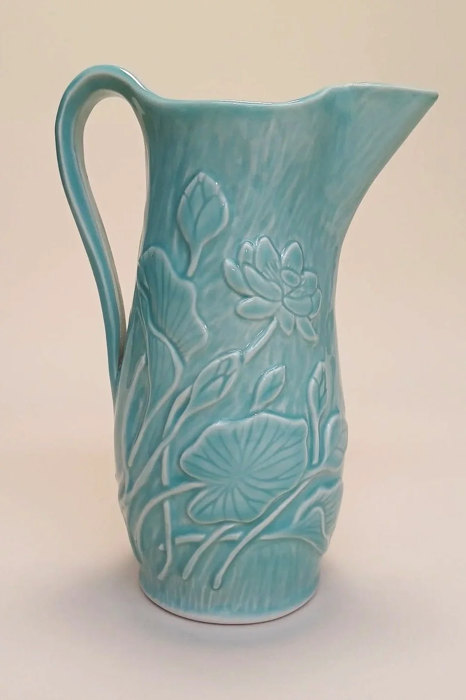 Light blue ceramic pitcher with hand carved lotus patterns.