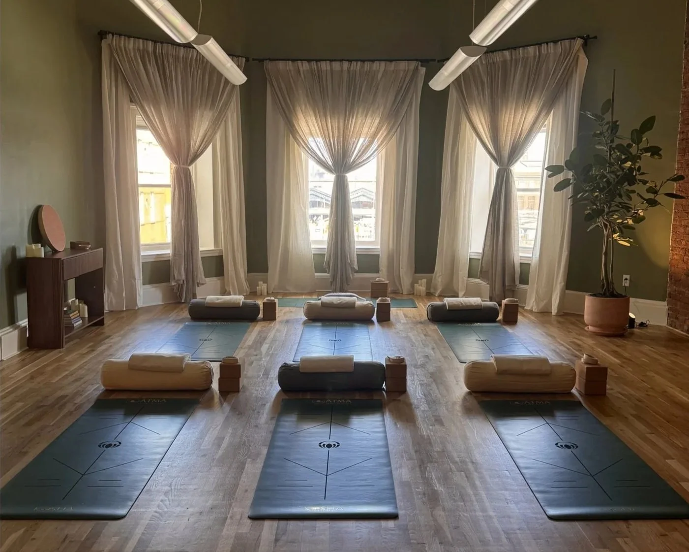 Main practice room at ĀTMĀ Yoga Collective — warm ambient light, natural materials, and intentionally simple design