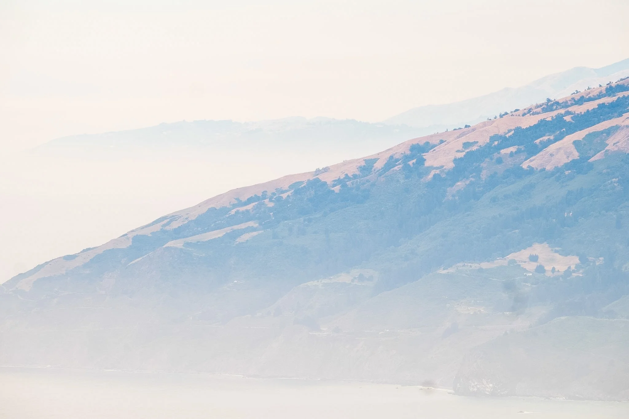 Hazy mountain landscape with rolling hills covered in grass and scattered trees