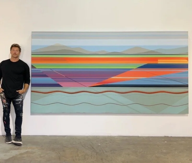 A man standing next to a large abstract landscape painting with mountains and colorful horizontal lines.