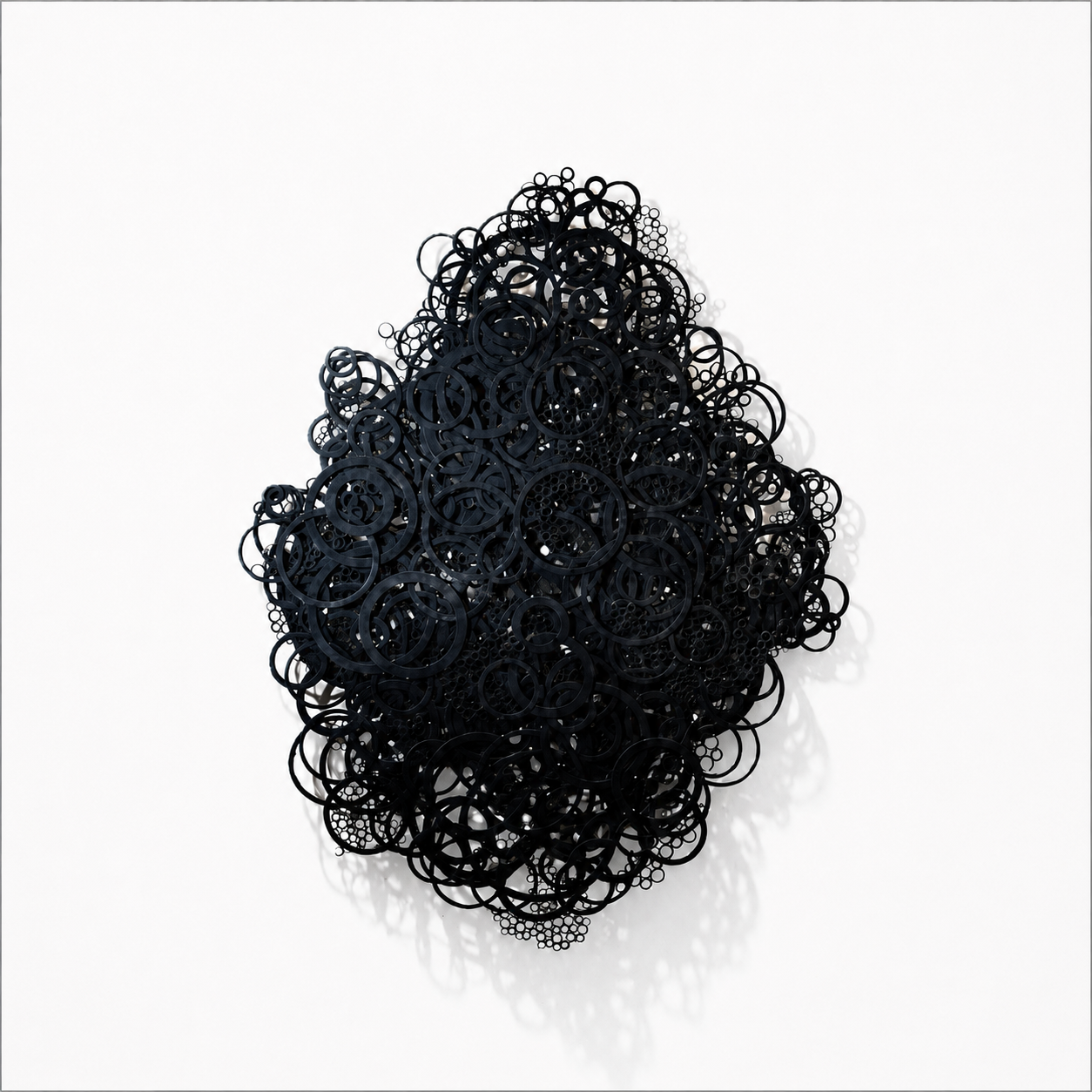 Abstract black circular shapes arranged in a dense cluster on a white background, casting shadows.