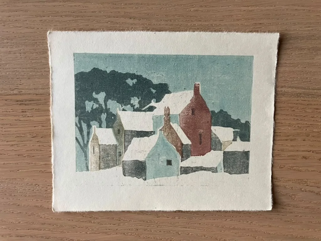 Color woodcut of a village with houses, trees, and snow on the roofs.