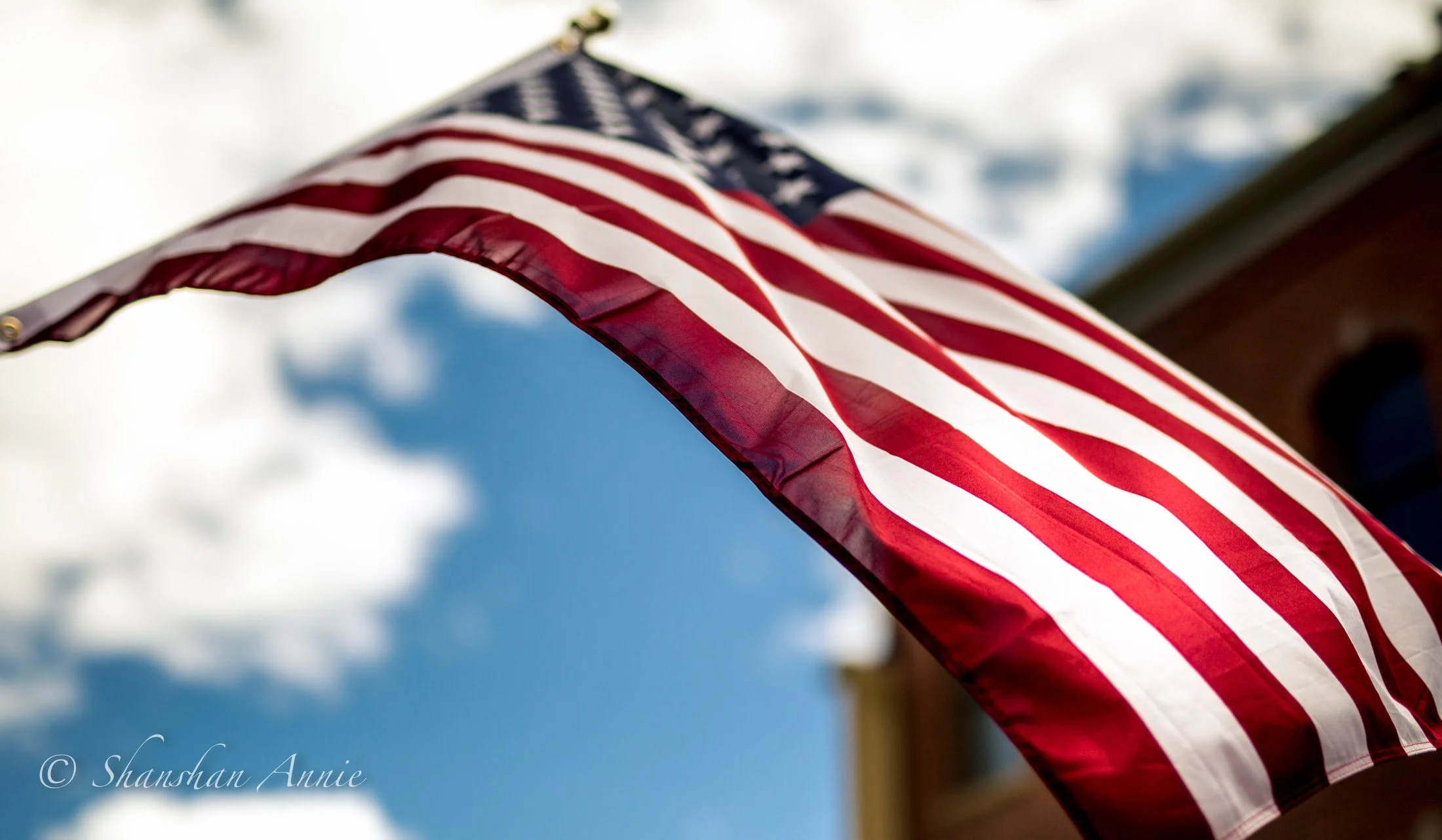 Close-up of an American flag waving outdoors against a cloudy sky.