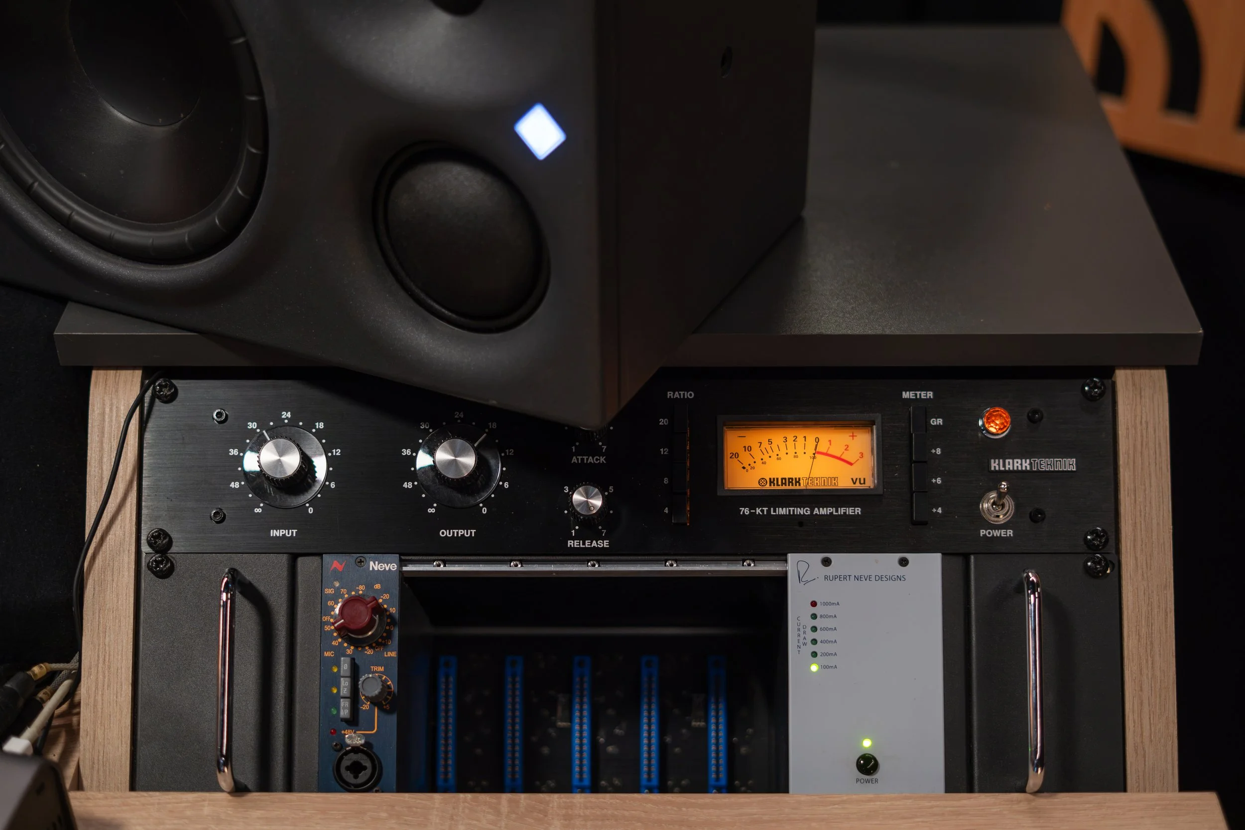 Un amplificateur audio avec deux haut-parleurs placés au-dessus et un équipement de réglage en dessous, posé sur un meuble en bois.